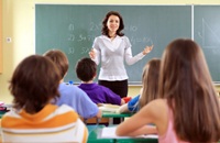 Classroom full of students facing blackboard and teacher