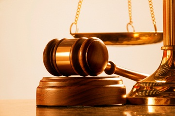 Gavel lying on a stand in front of a scale. 