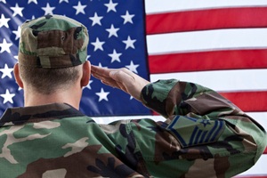 Military man saluting the American flag.